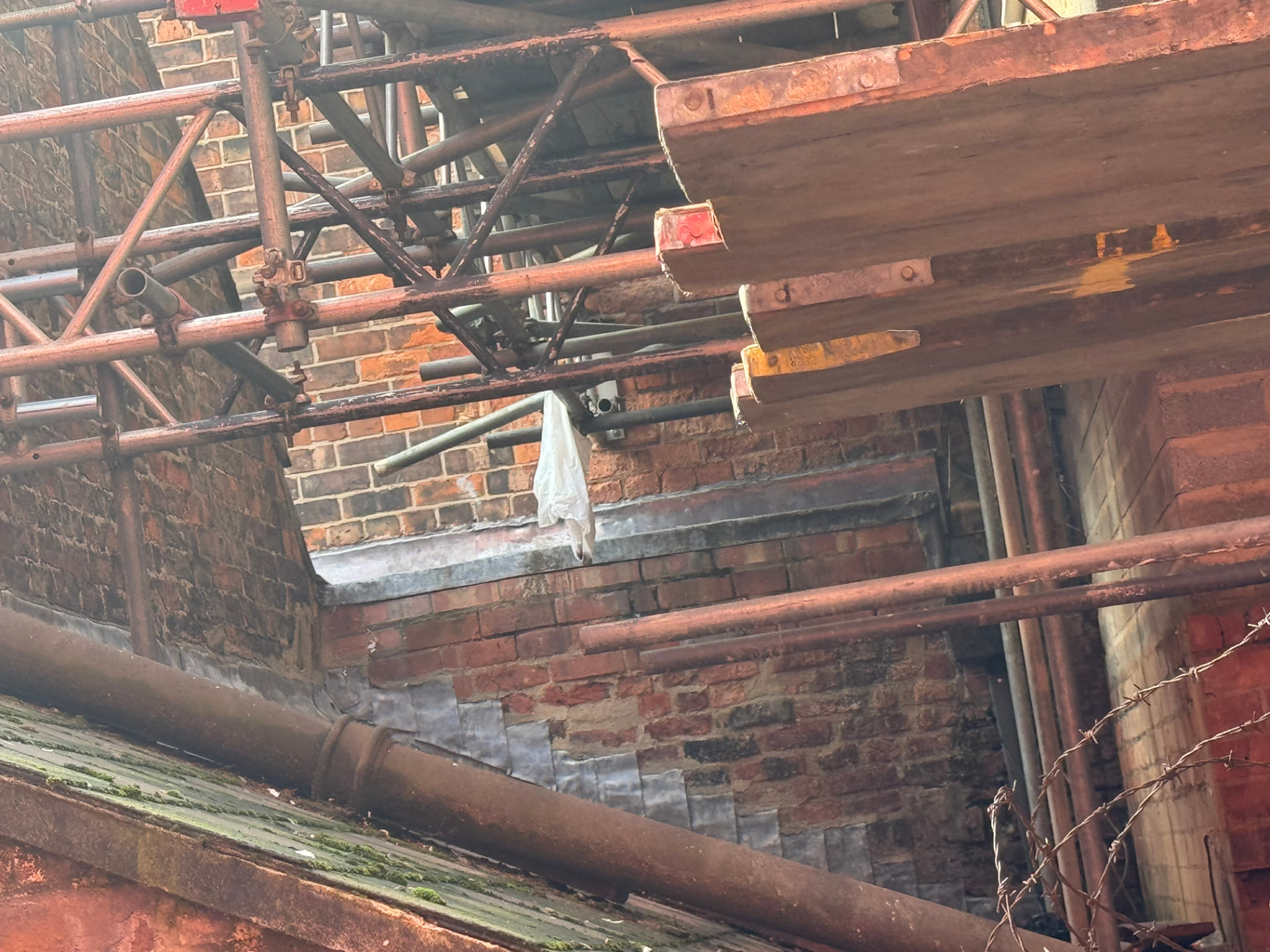 Close view of scaffold boards and tubes projecting over the neighbouring parapet